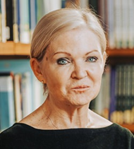 A headshot of Prof. Christine Cooper, looking at the camera in front of a blurred bookcase.